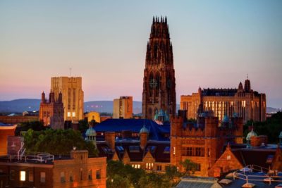 View of a cityscape with historic buildings and a prominent clock tower at sunset.