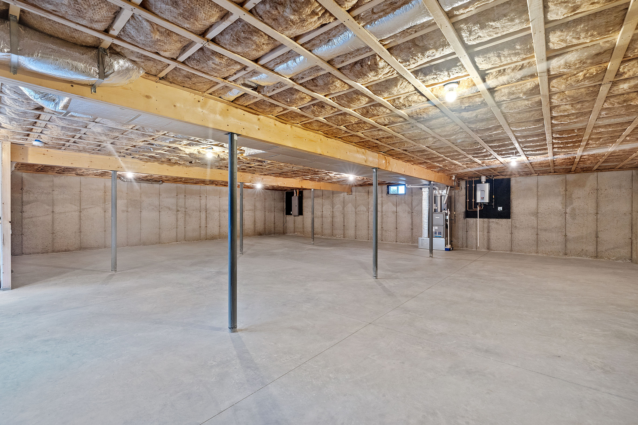 A spacious, unfinished basement with concrete floors, exposed beams, and insulation on the ceiling and walls, perfect for your next basement renovation CT project.