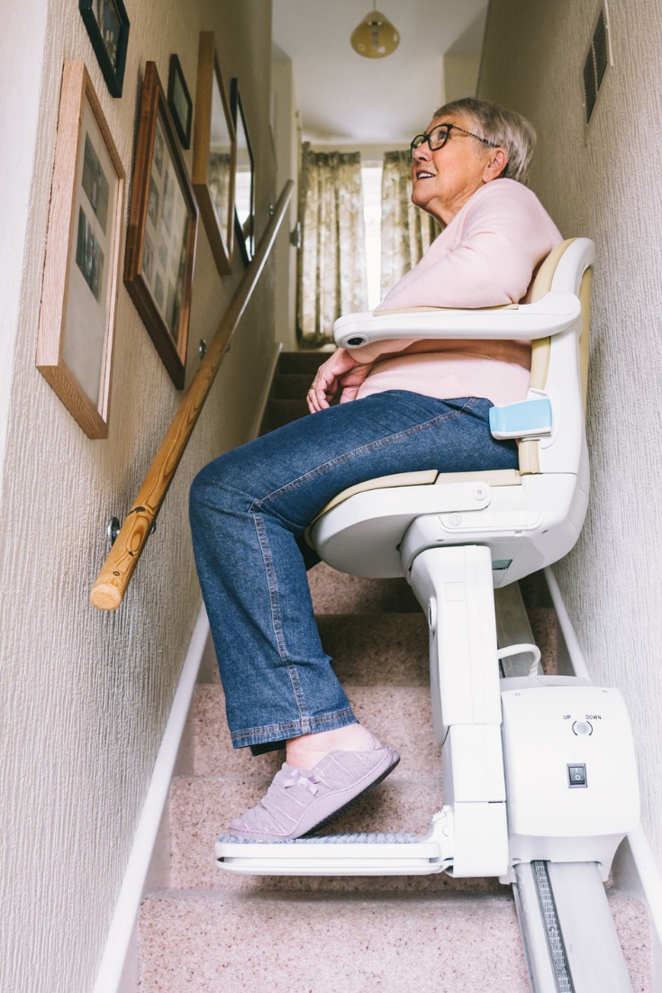 Elderly Woman using automatic stair lift at her home