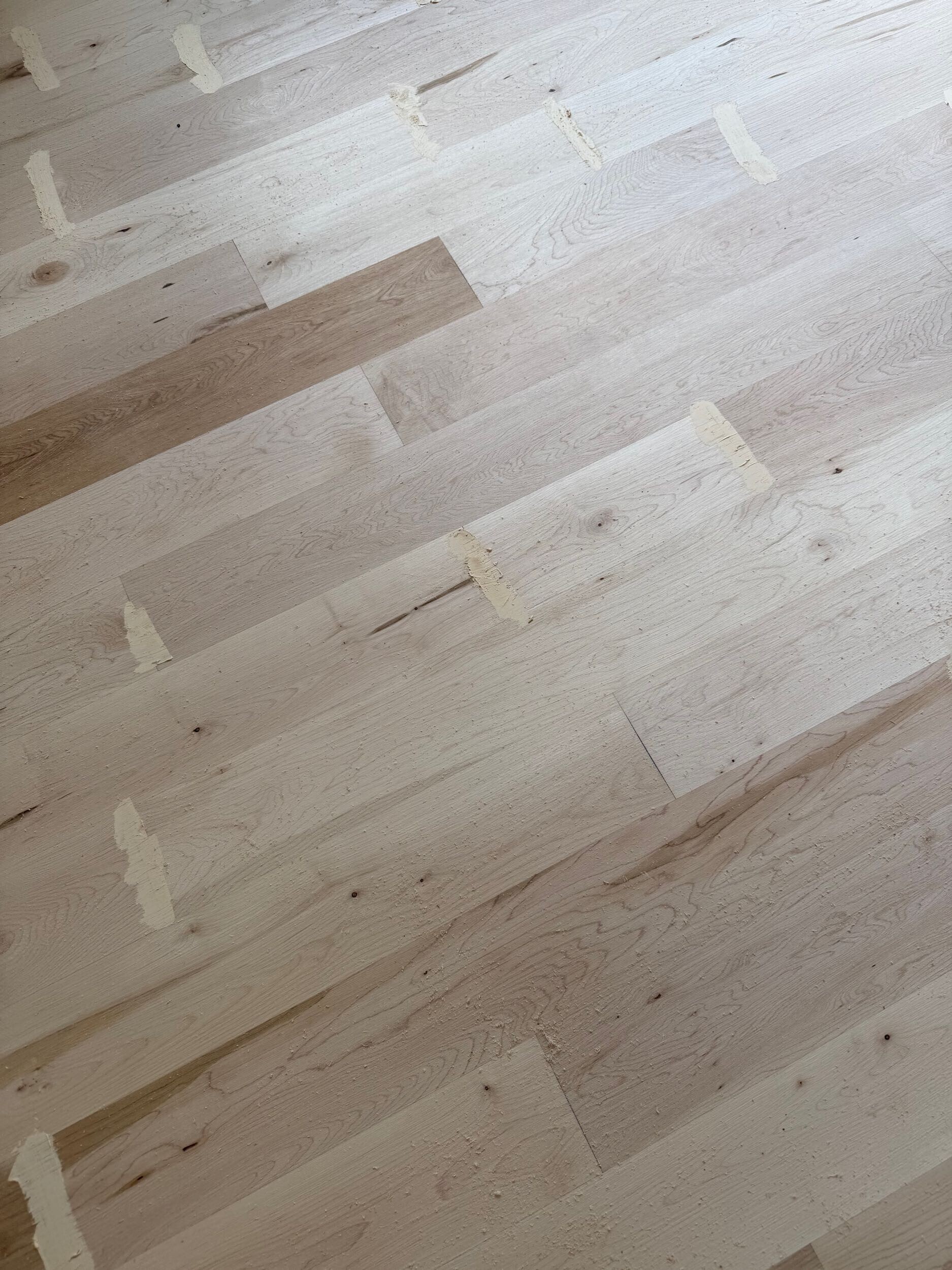 Close view of maple floor boards showing natural color variation and refinishing repairs