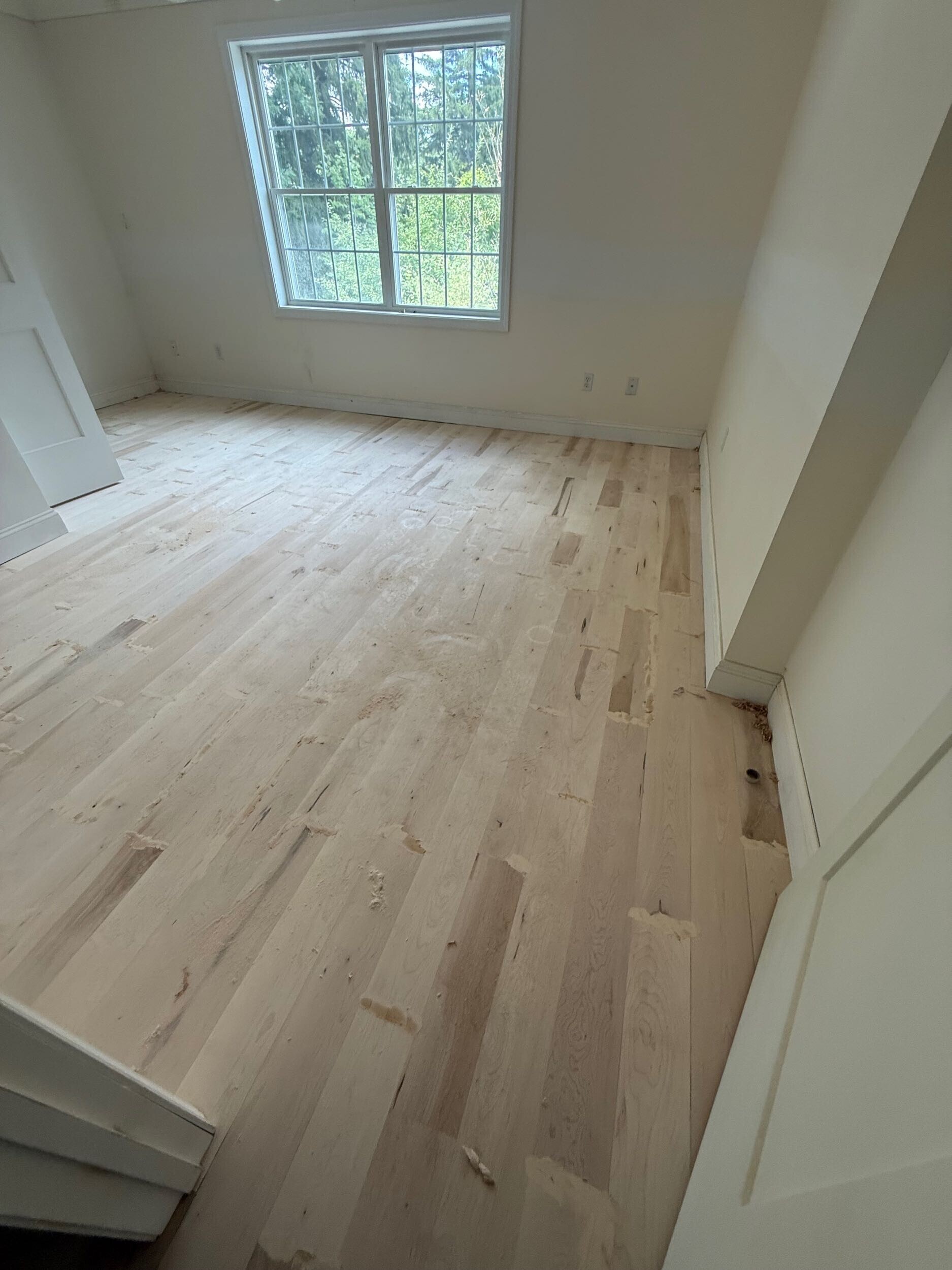 Light maple flooring after sanding and finish testing during a Connecticut remodel